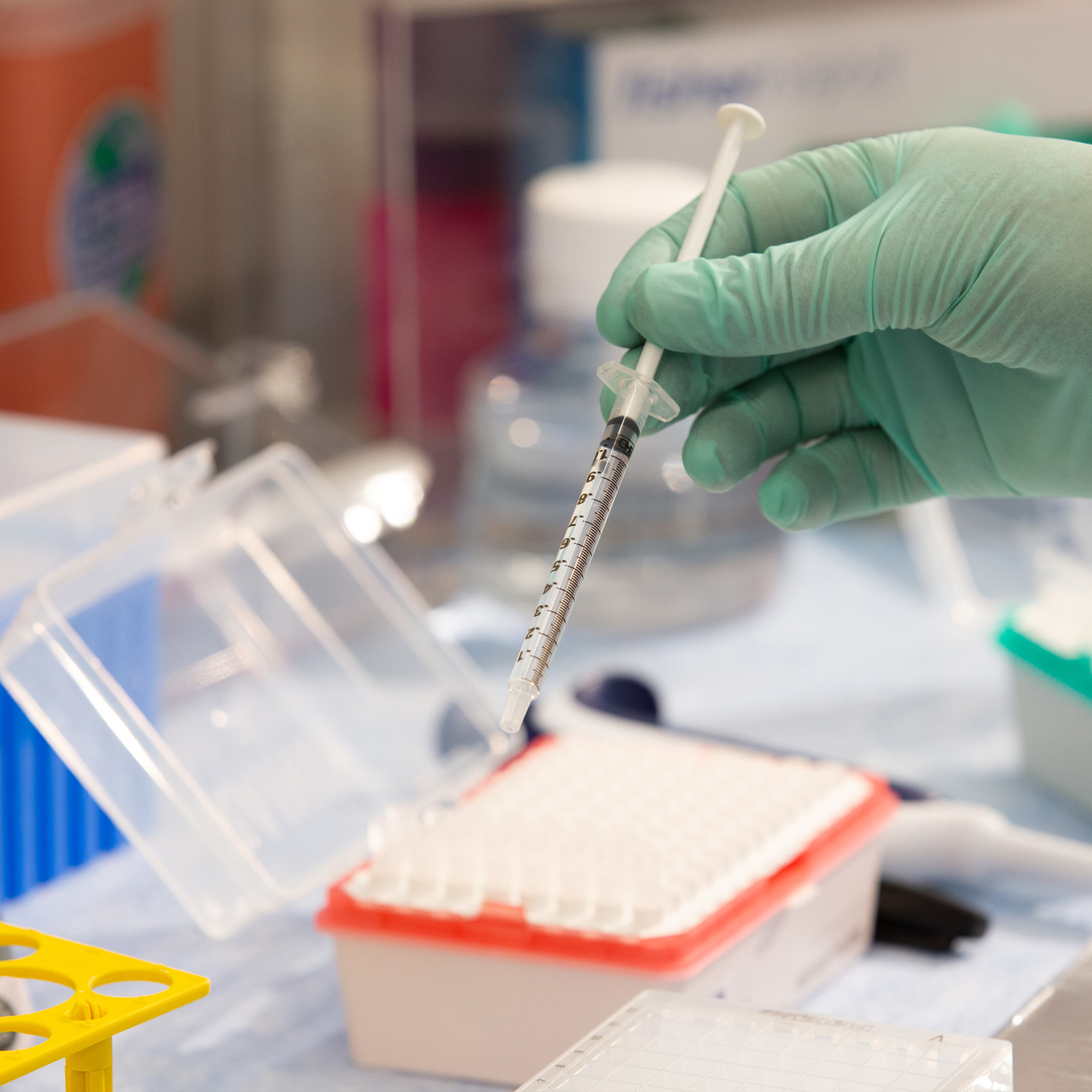 Alexion lab with a hand holding a syringe needle